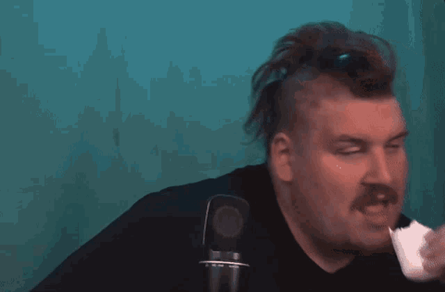 a man with a mustache stands in front of a microphone