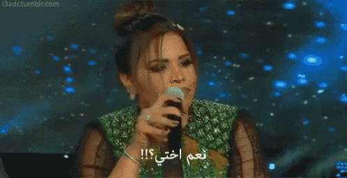 a woman is holding a microphone with arabic writing on it