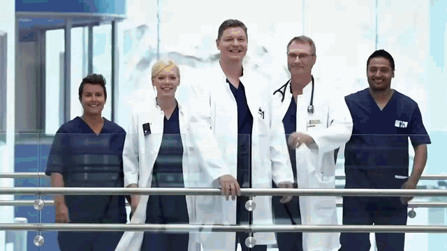 a group of doctors and nurses are standing next to each other on a balcony in a hospital .