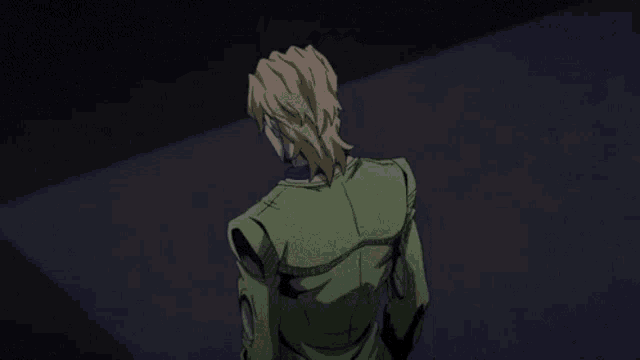 a man in a green jacket is standing in a dark room looking at something .