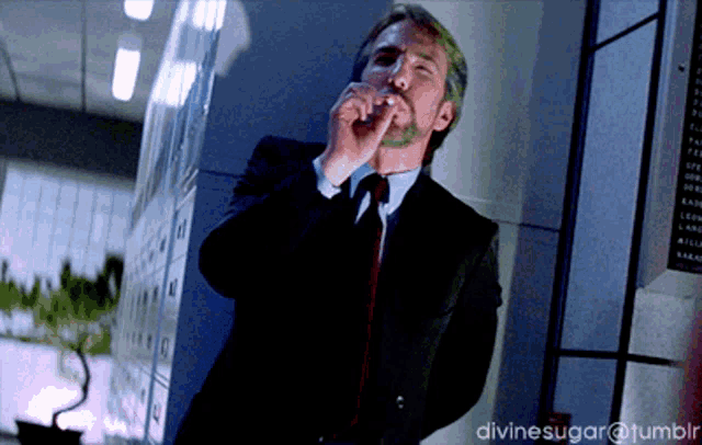 a man in a suit and tie smoking a cigarette with divinesugar @ tumblr written below him