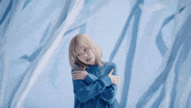 a woman with blonde hair is wearing a blue dress