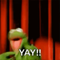 kermit the frog from the muppet show is standing in front of a red curtain and saying yay !