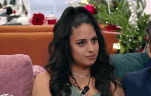 a woman is sitting on a couch in front of a christmas tree and looking at the camera .