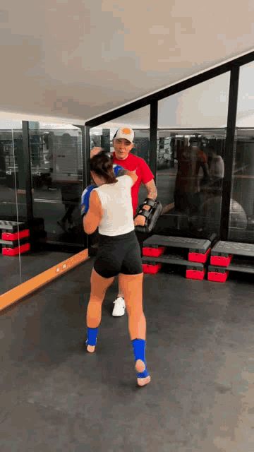 a man and a woman are boxing in front of a mirror in a gym
