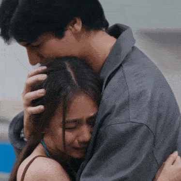 a man in a leather jacket is hugging a woman