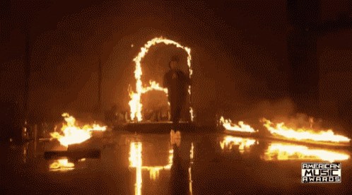 a man is standing in front of a flame that says american music awards on it