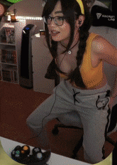 a woman wearing glasses and a braided headband is sitting in front of a video game controller