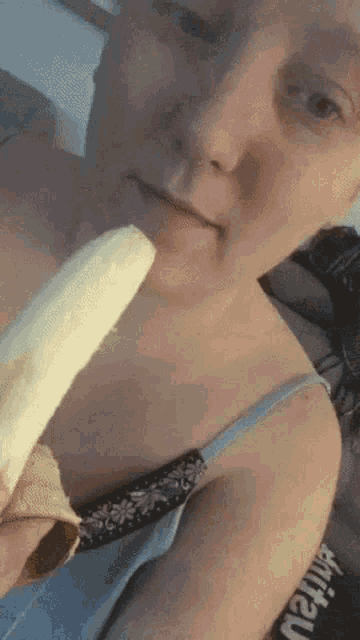 a woman is eating a banana and taking a selfie .