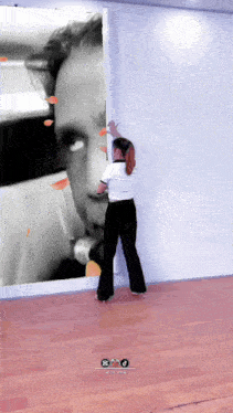 a woman leans against a wall with a large picture of a man on it
