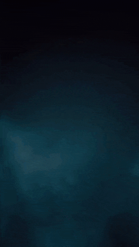 a man with a beard is standing in a dark room holding a knife