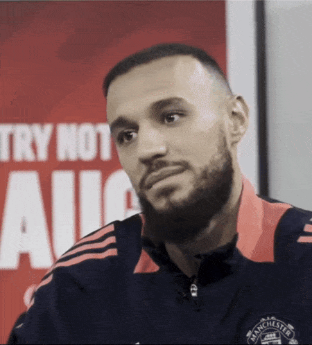 a man with a beard wearing a manchester united jacket