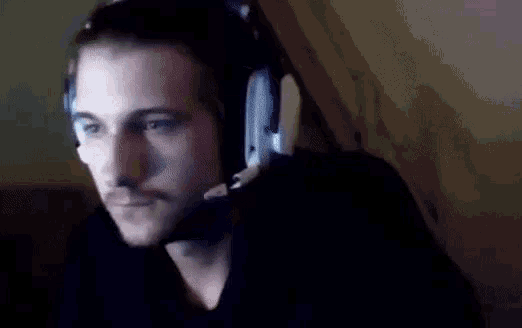 a man wearing headphones with a microphone on his head is looking at the camera .