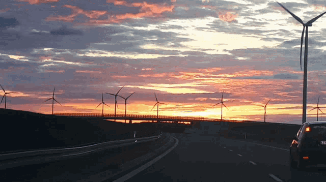 a car driving down a highway with windmills in the background