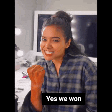 a woman in a plaid shirt is making a fist in the air and smiling .