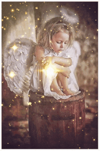 a little girl with angel wings sitting on a wooden barrel