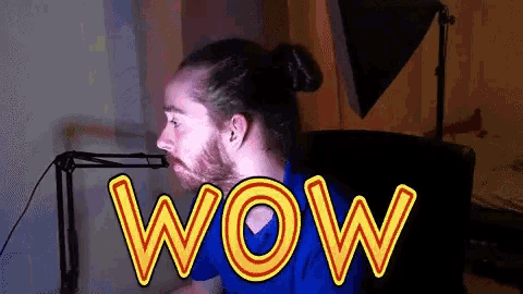 a man in a blue shirt is sitting in front of a microphone with the word wow written on it