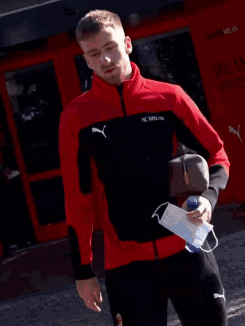 a man wearing a red and black jacket with ac milan written on it