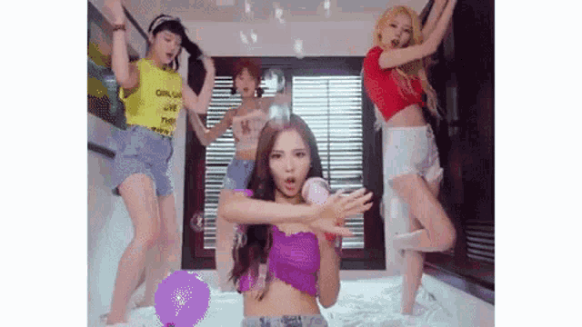 a group of young women are dancing on a bed with balloons in a room .