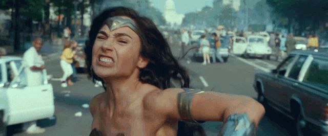 a woman in a wonder woman costume is running down a street with cars .