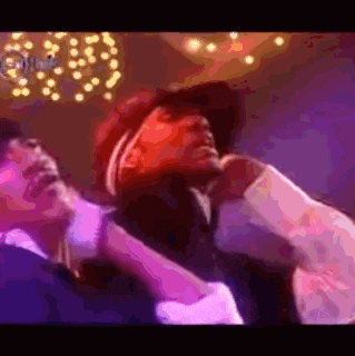 a man in a red hat is singing into a microphone in a purple room .