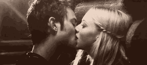 a man and a woman are kissing in front of a wall in a black and white photo .