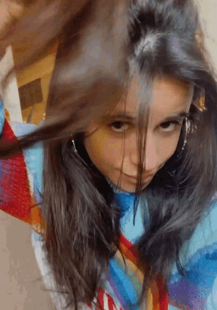 a close up of a woman 's face with a rainbow colored shirt on