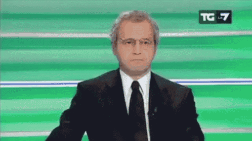a man in a suit and tie is standing in front of a green background with the letters tg on it .