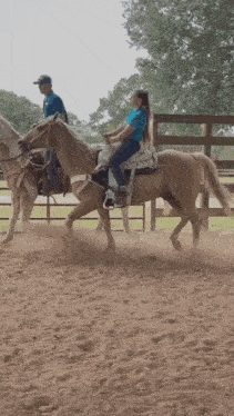 a woman in a blue shirt is riding a brown horse
