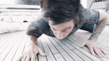 a man with a tattoo on his arm is doing push ups on the floor