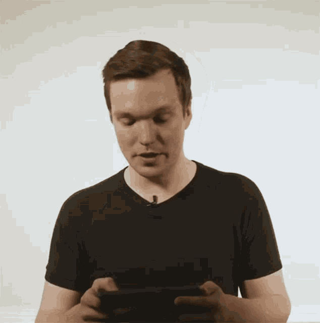 a man in a black shirt is looking at a cell phone
