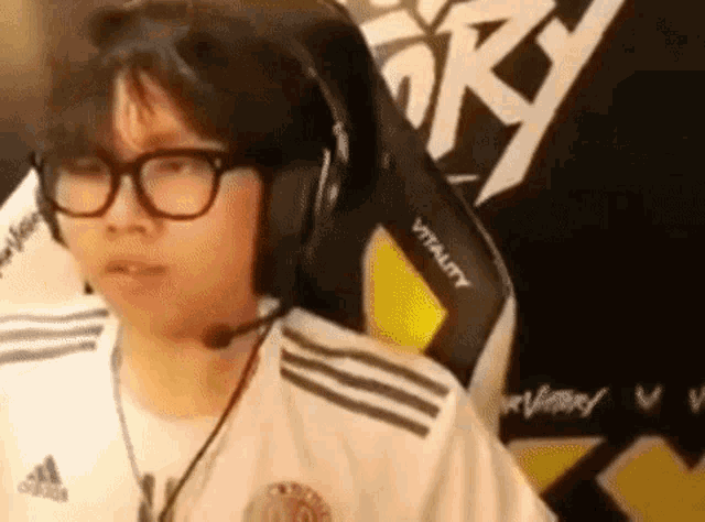 a man wearing glasses and headphones is sitting in a chair with a microphone .