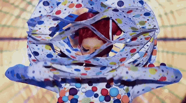 a woman with red hair is wrapped in a colorful blanket
