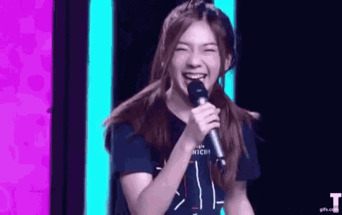 a young woman is holding a microphone in her hand and smiling .