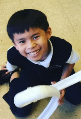 a young boy is sitting on the floor holding a white balloon and smiling .