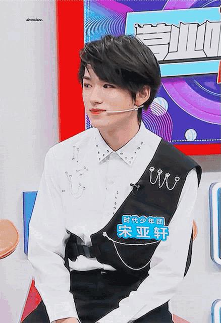 a young man wearing a white shirt and a black vest has a name tag that says ' iu ' on it
