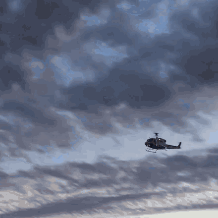 a helicopter is flying through a cloudy sky at sunset