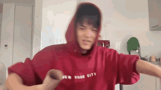 a man is wearing a red hoodie that says new york city