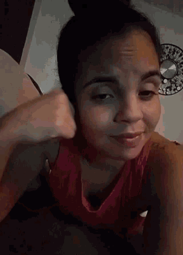 a woman in a red tank top gives a thumbs up sign