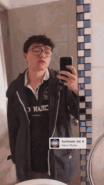 a young man taking a picture of himself in front of a mirror with a harry styles song playing on the phone