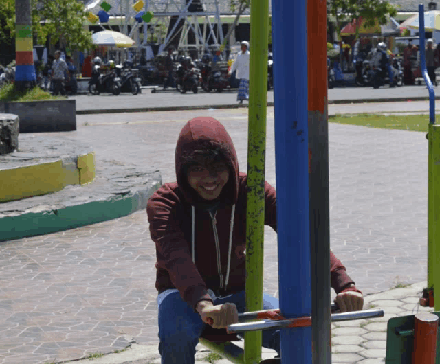 a man wearing a red hoodie is sitting on a machine