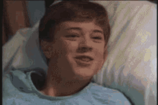 a young man is laying in a hospital bed smiling