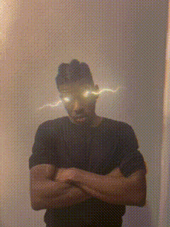 a man in a black shirt is standing with his arms crossed in front of a wall with glowing eyes .