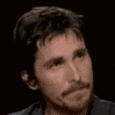 a man with a beard is looking at the camera with a serious look on his face