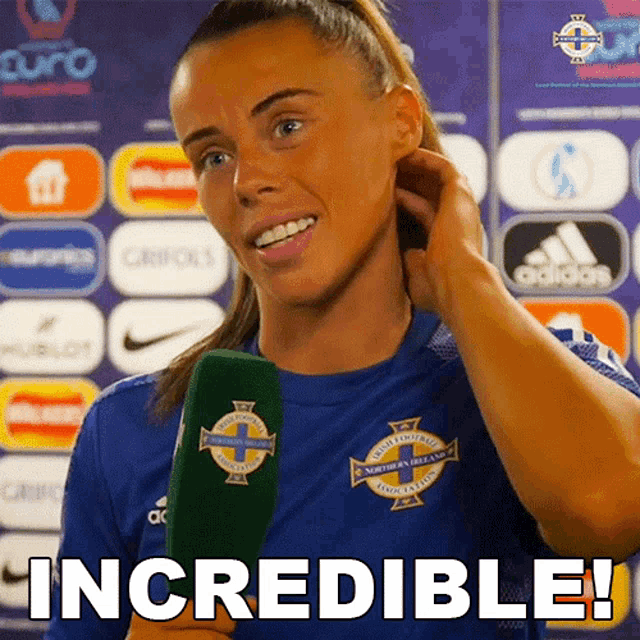 a woman in a blue shirt is holding a green microphone and says " incredible "