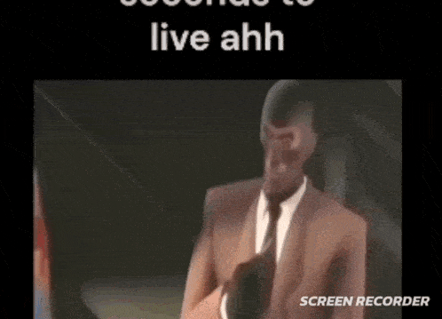 a man in a suit and tie is standing in front of a screen with the words `` live ahh '' written on it .