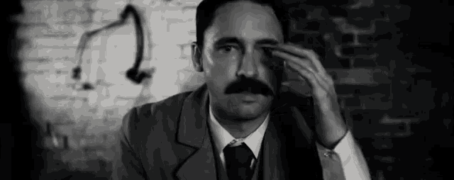 a black and white photo of a man with a mustache covering his eyes .