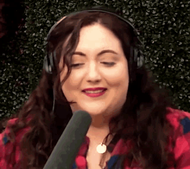 a woman wearing headphones and a microphone looks at the camera