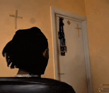 a man sitting in front of a door with a cross on the wall