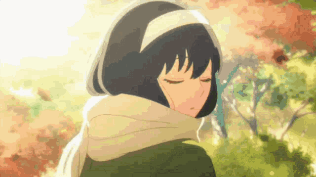 a girl wearing a scarf and a headband looks down with her eyes closed